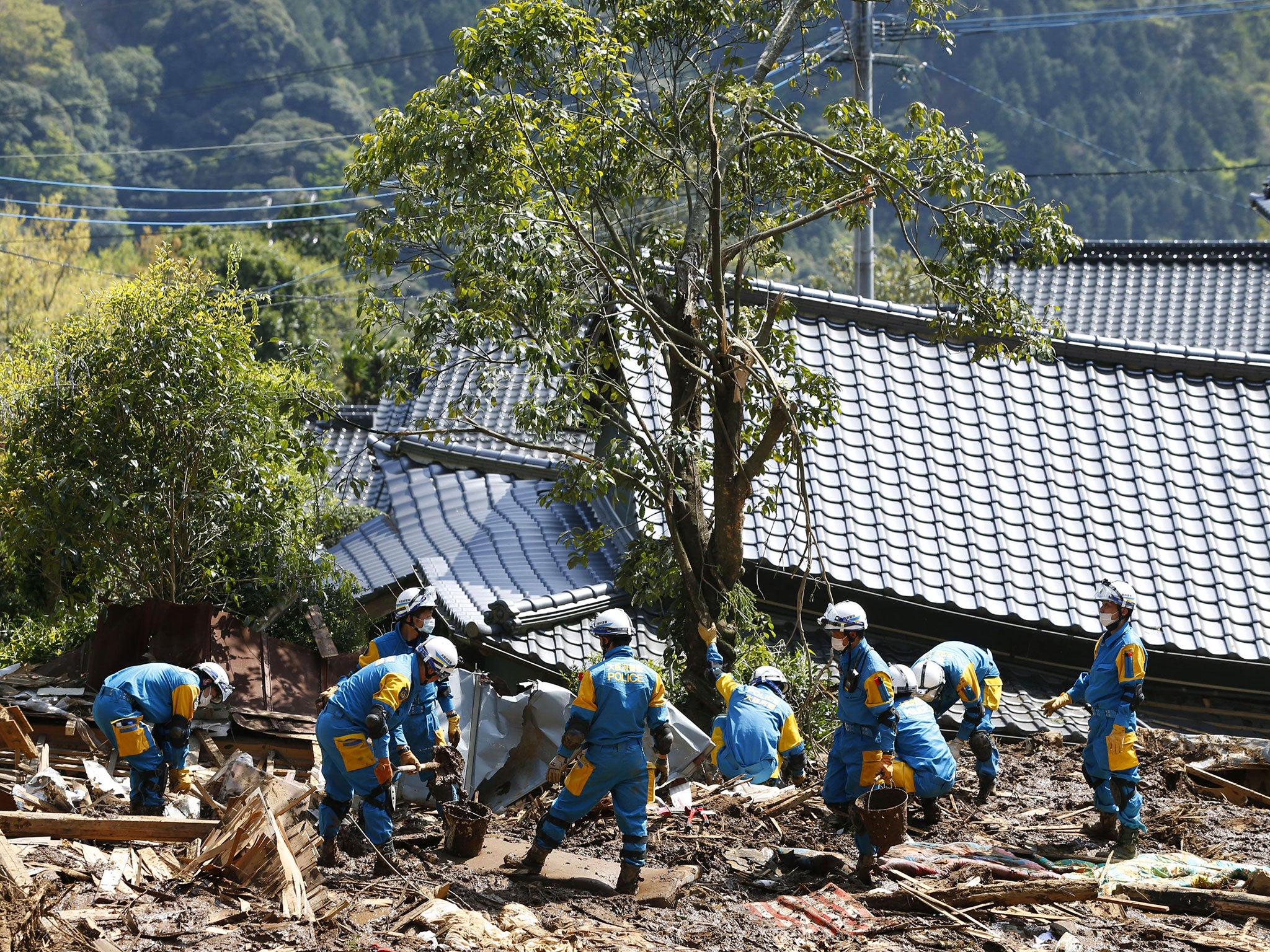 Police officers conduct a search operation near the damaged houses in Minamiaso, Kumamoto prefecture