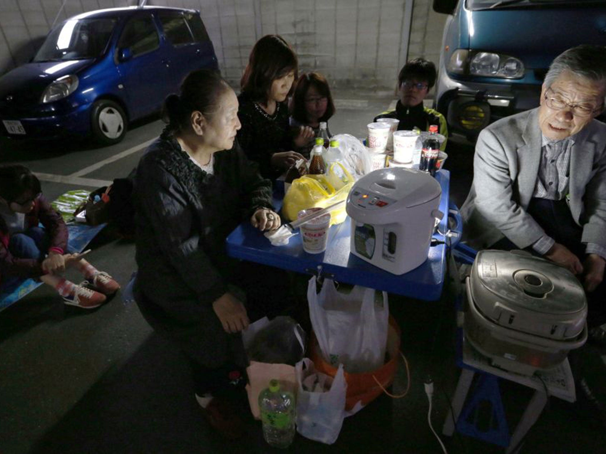 A displaced family wait in a car park to avoid being hurt by falling buildings