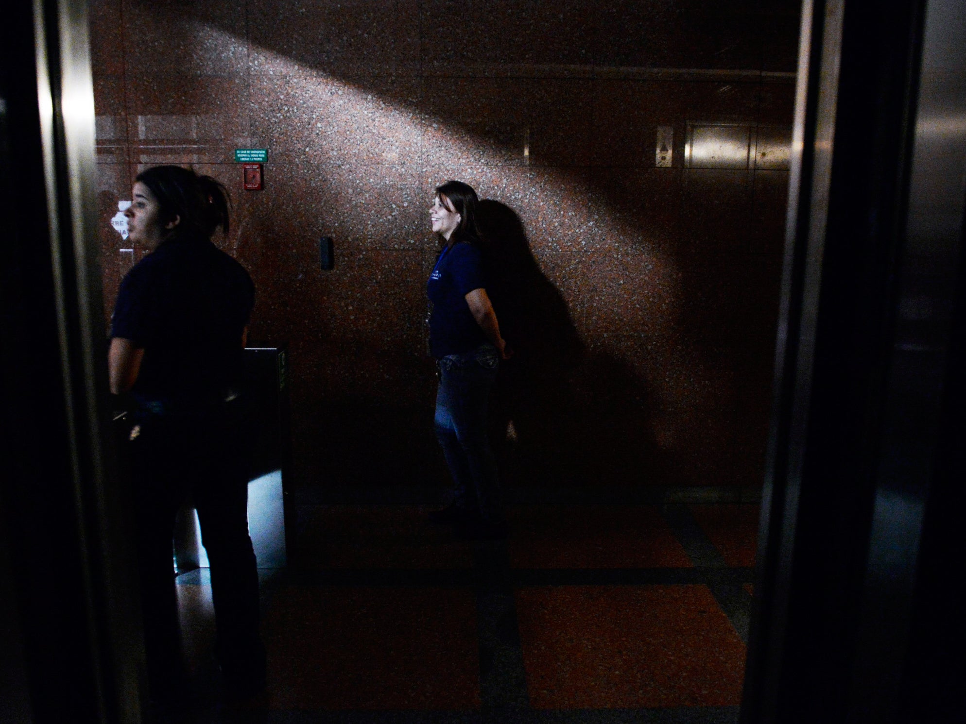 People stand on the corridor of a building during a blackout in Caracas