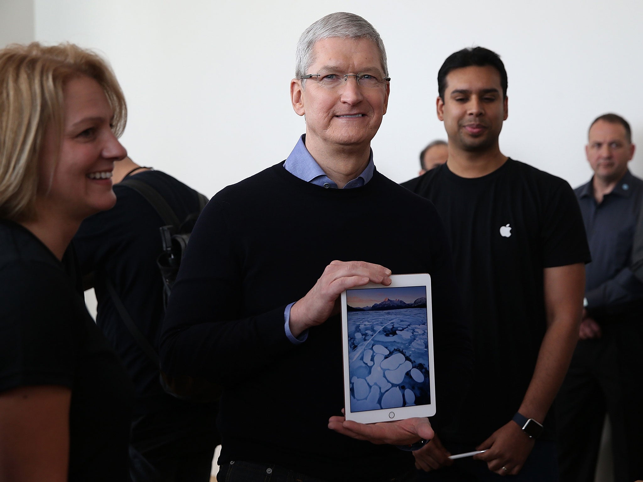 Apple CEO Tim Cook holding an iPad. The company expects users to replace their iPhone, iPad or Apple Watch device every three years