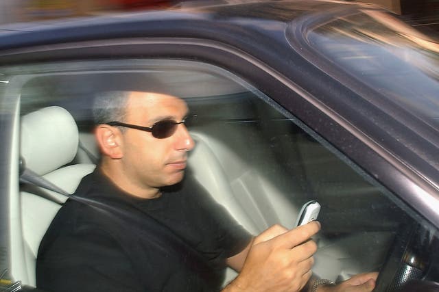 A man uses a phone while driving in London in 2003, shortly before the ban came into force
