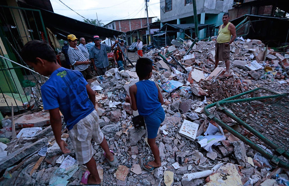 People stand outside their fallen homes in Manta.