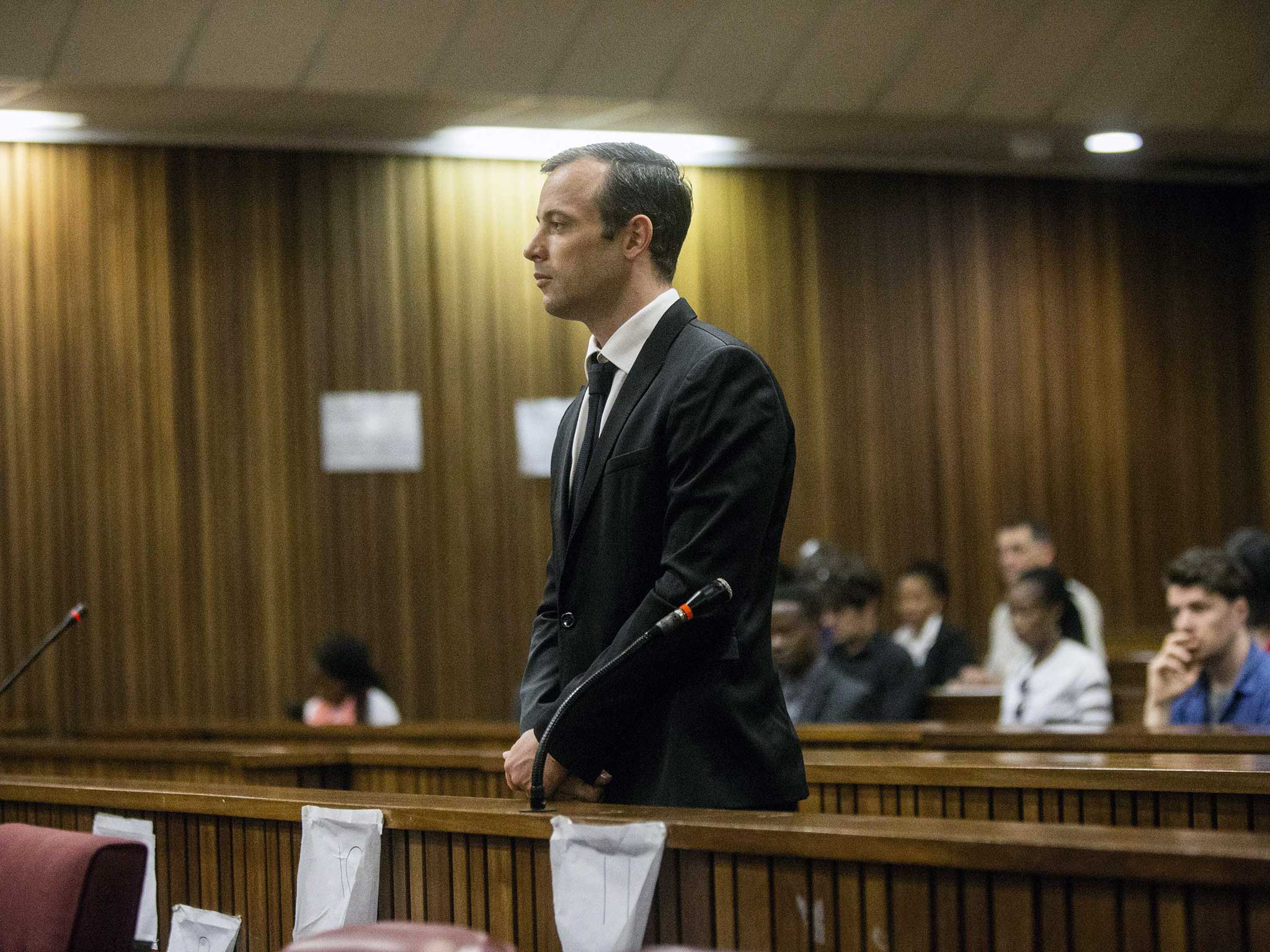 Oscar Pistorius stands in the dock at the High Court in Pretoria ahead of postponement hearing