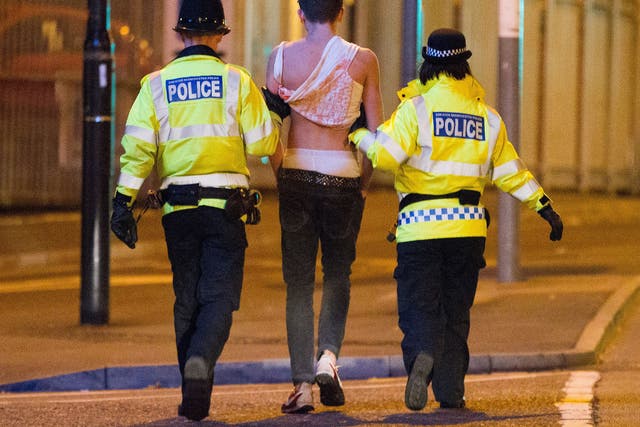 A drunk student is led away by police officers in Manchester