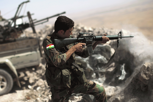 An Iraqi Kurdish peshmerga fighter fires on an Isis position JM LOPEZ/AFP/Getty Images
