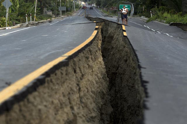 Residents look at a rift in the highway created by a 7.8-magnitude earthquake, in Chacras, Ecuador