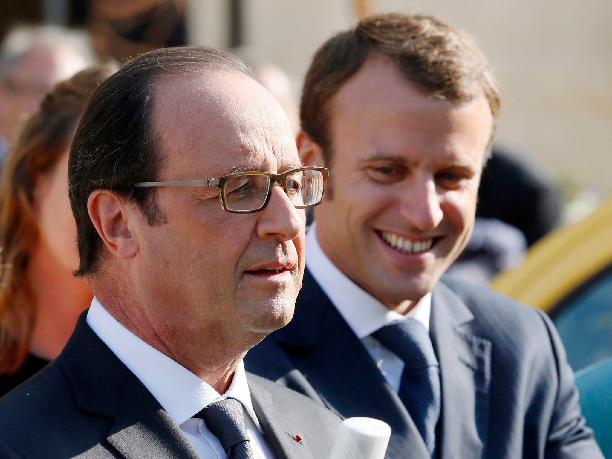 Economy minister Emmanuel Macron French, right, smiles during a speech by President François Hollande in the Elysee Palace gardens, but tensions between the two men appear to be rising