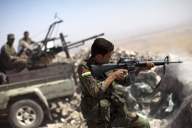 An Iraqi Kurdish Peshmerga fighter fires at Isis positions from the top of Mount Zardak