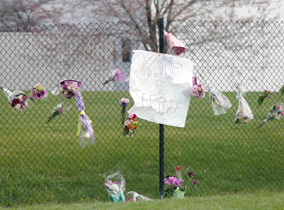 Flowers and a sign appear on the fence at Paisley Park Studios, the home and studio of singer Prince