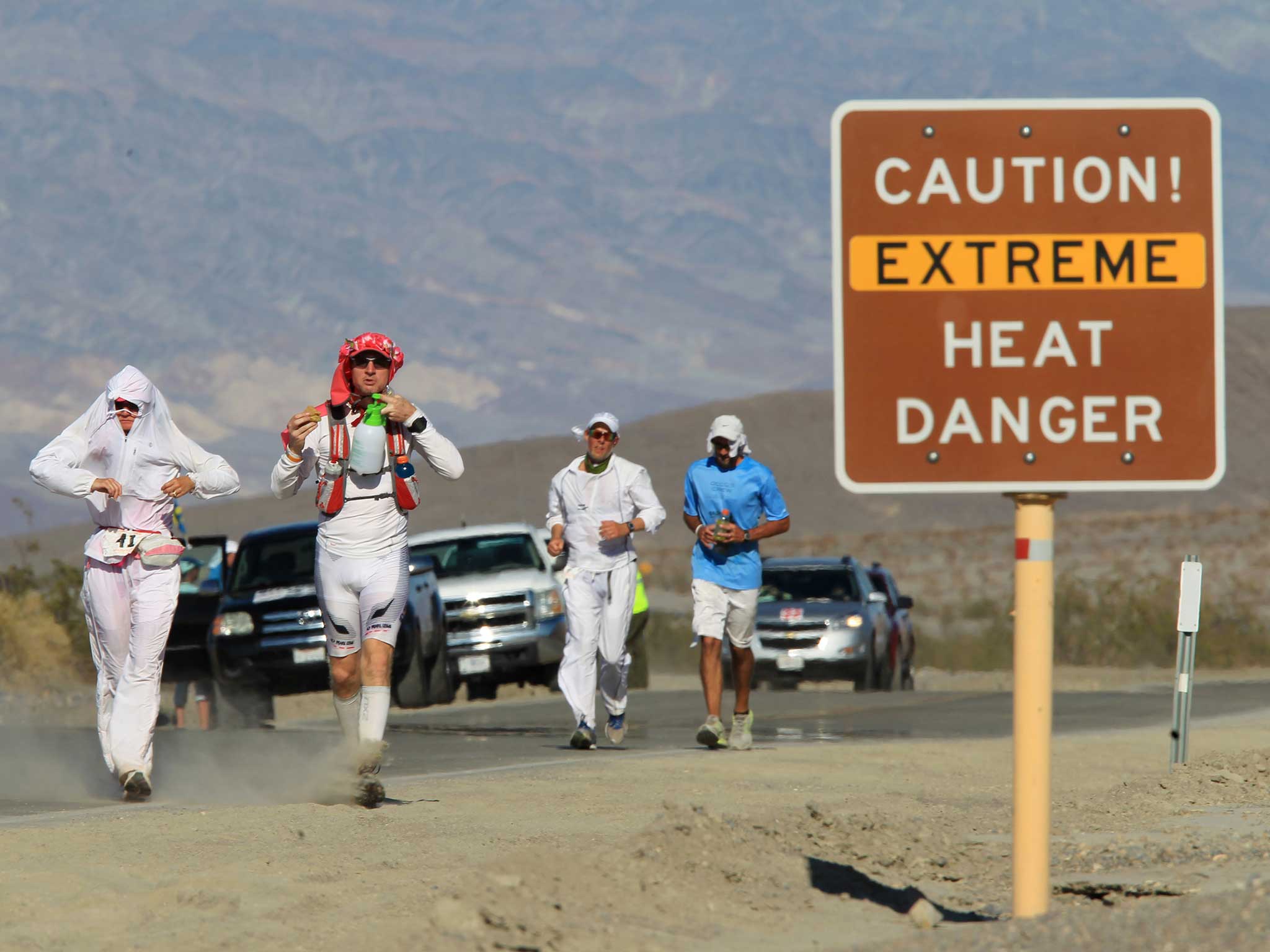 <p>Runners pass a heat danger warning sign during an ultra-marathon race in Death Valley National Park, California</p>
