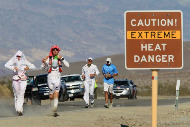 <p>Runners pass a heat danger warning sign during an ultra-marathon race in Death Valley National Park, California</p>