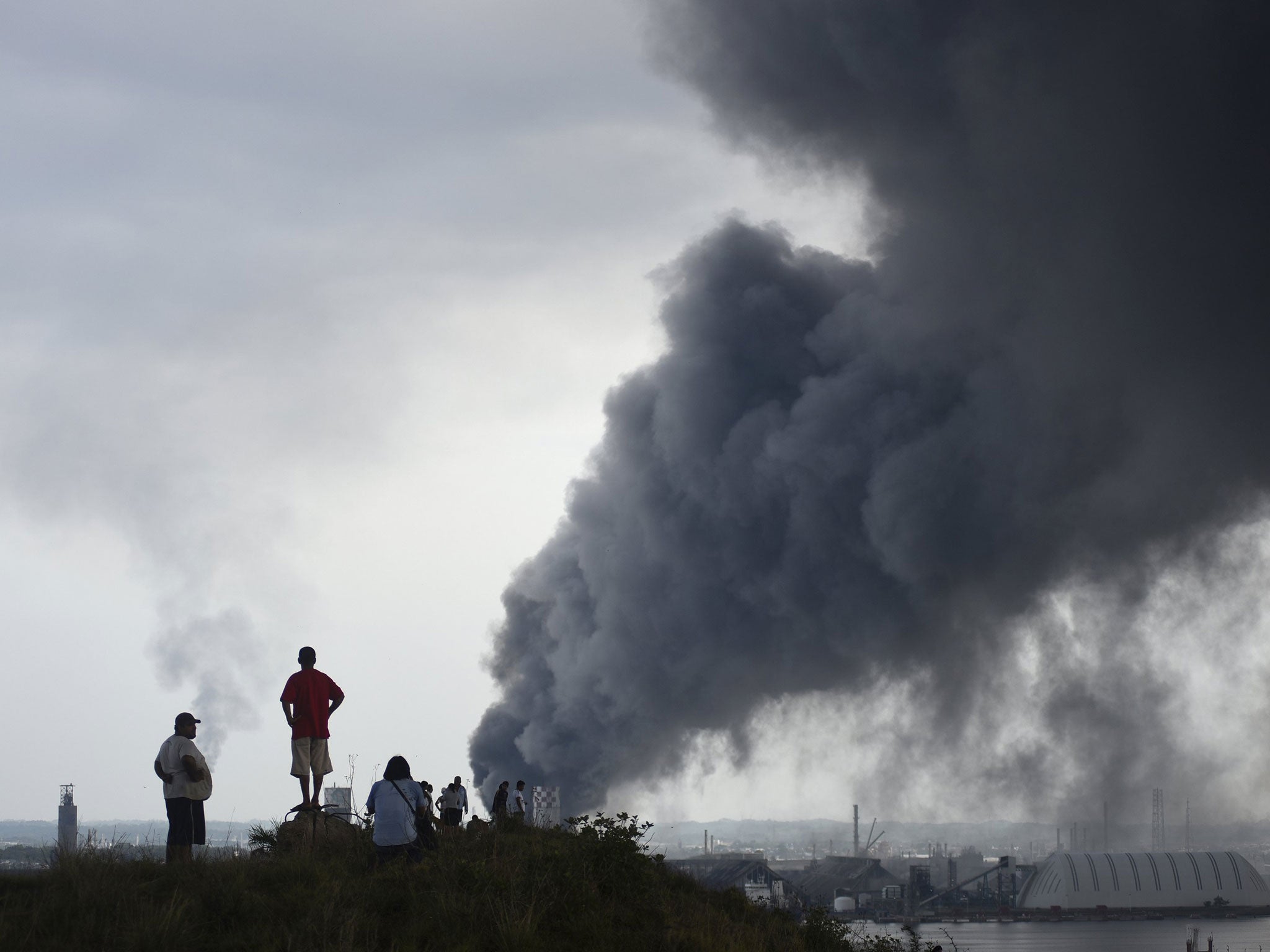 Residents look at smoke rising from the Pemex explosion site
