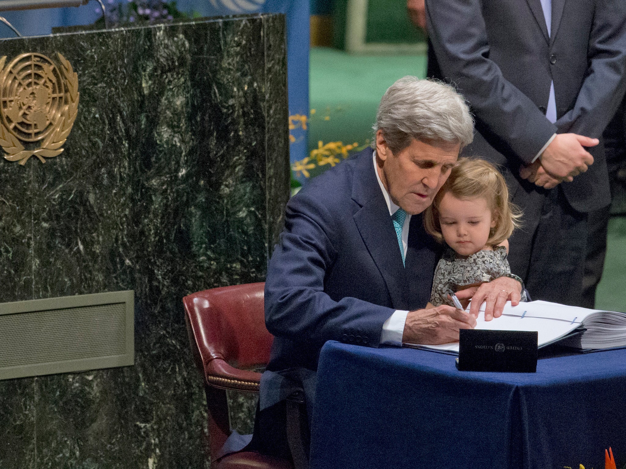 Secretary of State John Kerry holds his granddaughter while signing the climate change deal AP