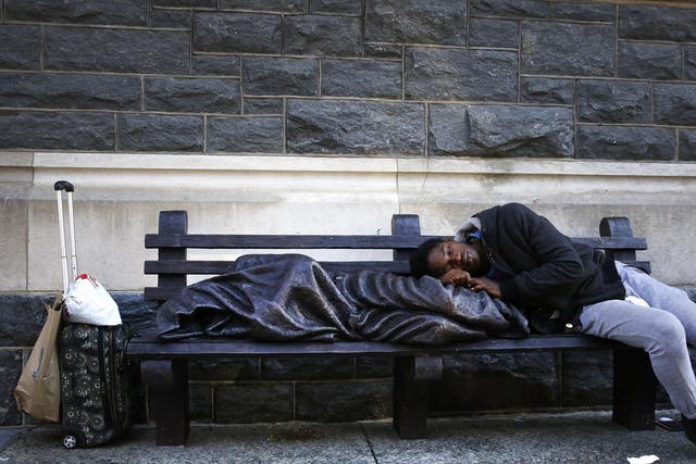  A man sleeps on a sculpture of a figure called 'Homeless Jesus' in front of the Archdiocese of Washington Catholic Charities offices in Washington DC, USA