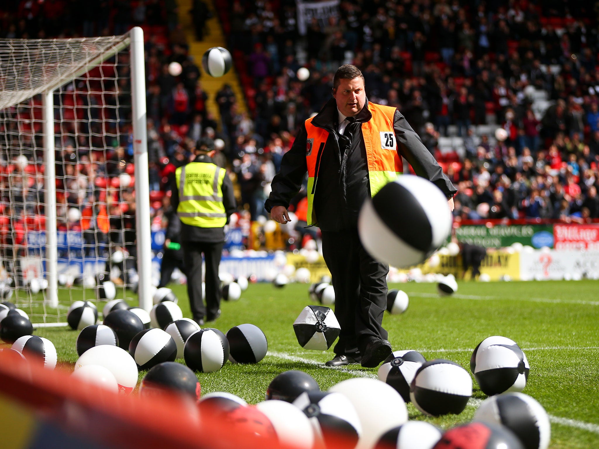 Charlton stewards clear beach balls from the pitch