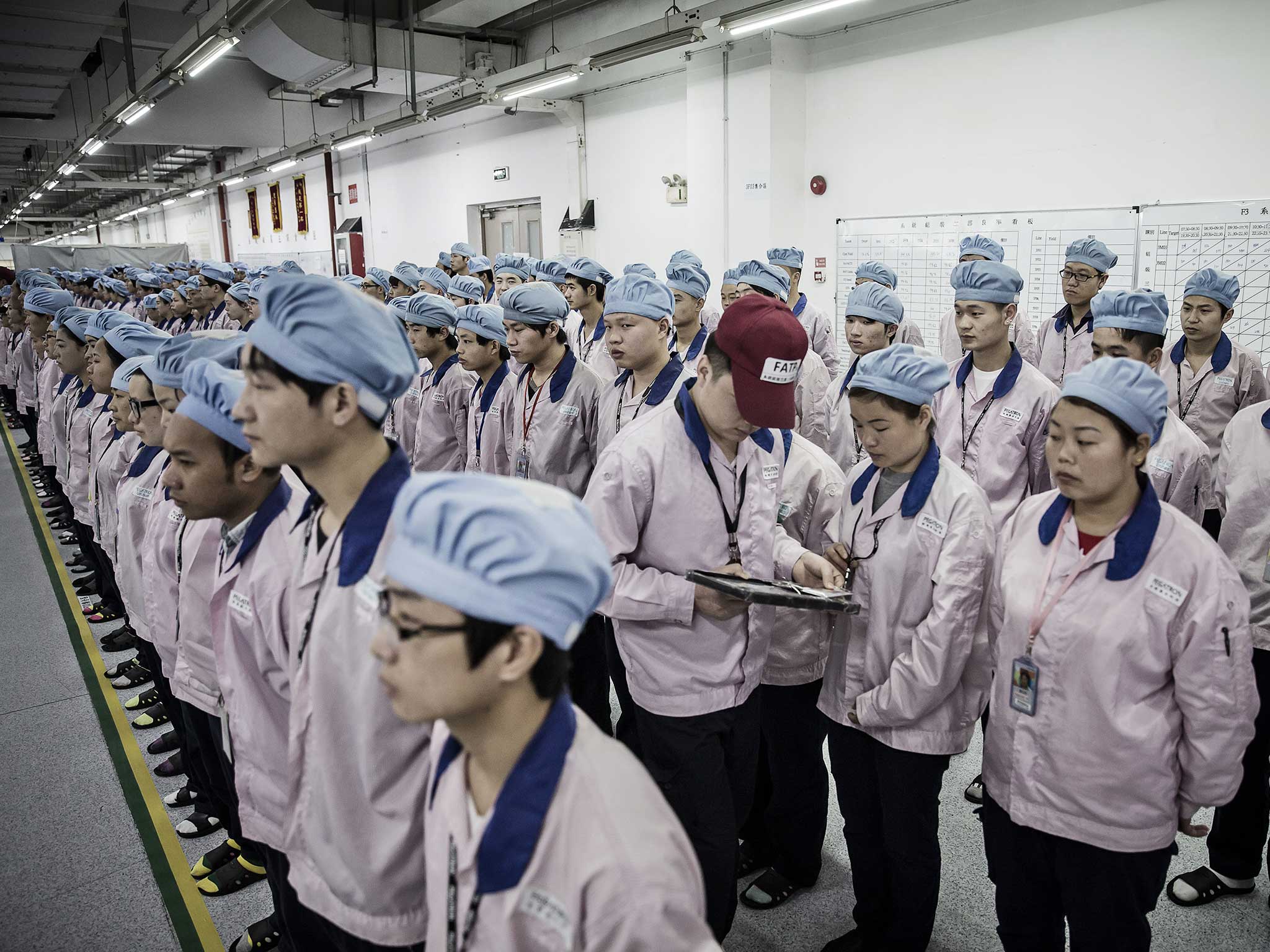 A supervisor holds an Apple Inc. iPad as he checks an employee's badge during roll call at a Pegatron Corp. factory in Shanghai, China