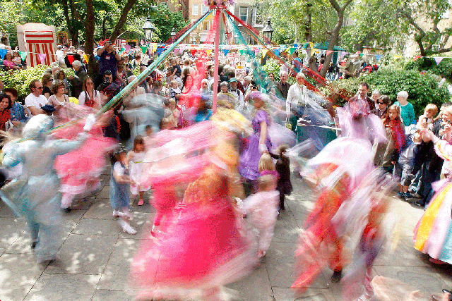 Children dressed as May Queens dance around a maypole in Covent Garden, London