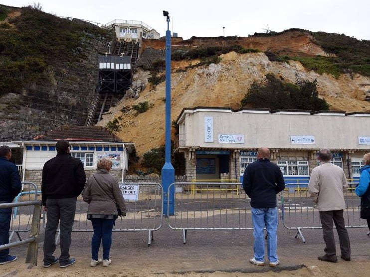 Members of the public look up at the collapsed cliff next to the East Cliff funicular railway on Bournemouth Beach