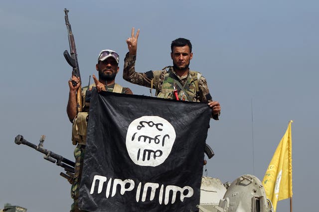 Iraqi Shiite fighters hold a captured Isis flag upside-down after an October 2015 operation