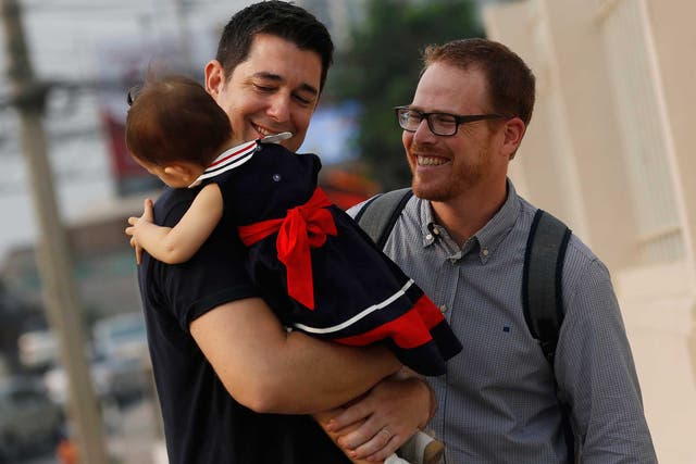 American Gordon Lake (L) and Spaniard Manuel Santos walk with their baby Carmen at the Central Juvenile and Family Court in Bangkok, Thailand
