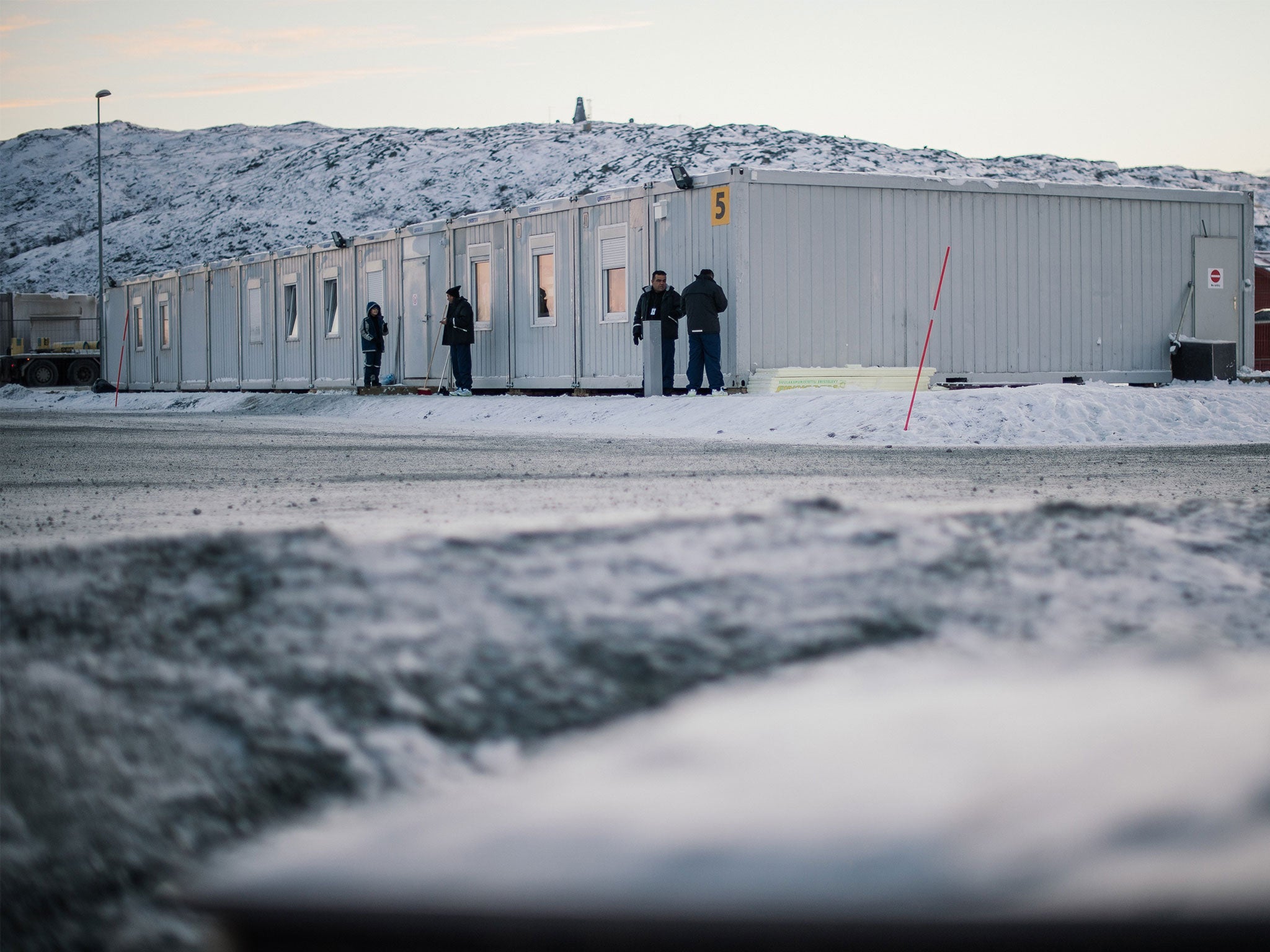 Refugees stand in front of residential containers at the arrival centre for refugees near the town on Kirkenes, northern Norway