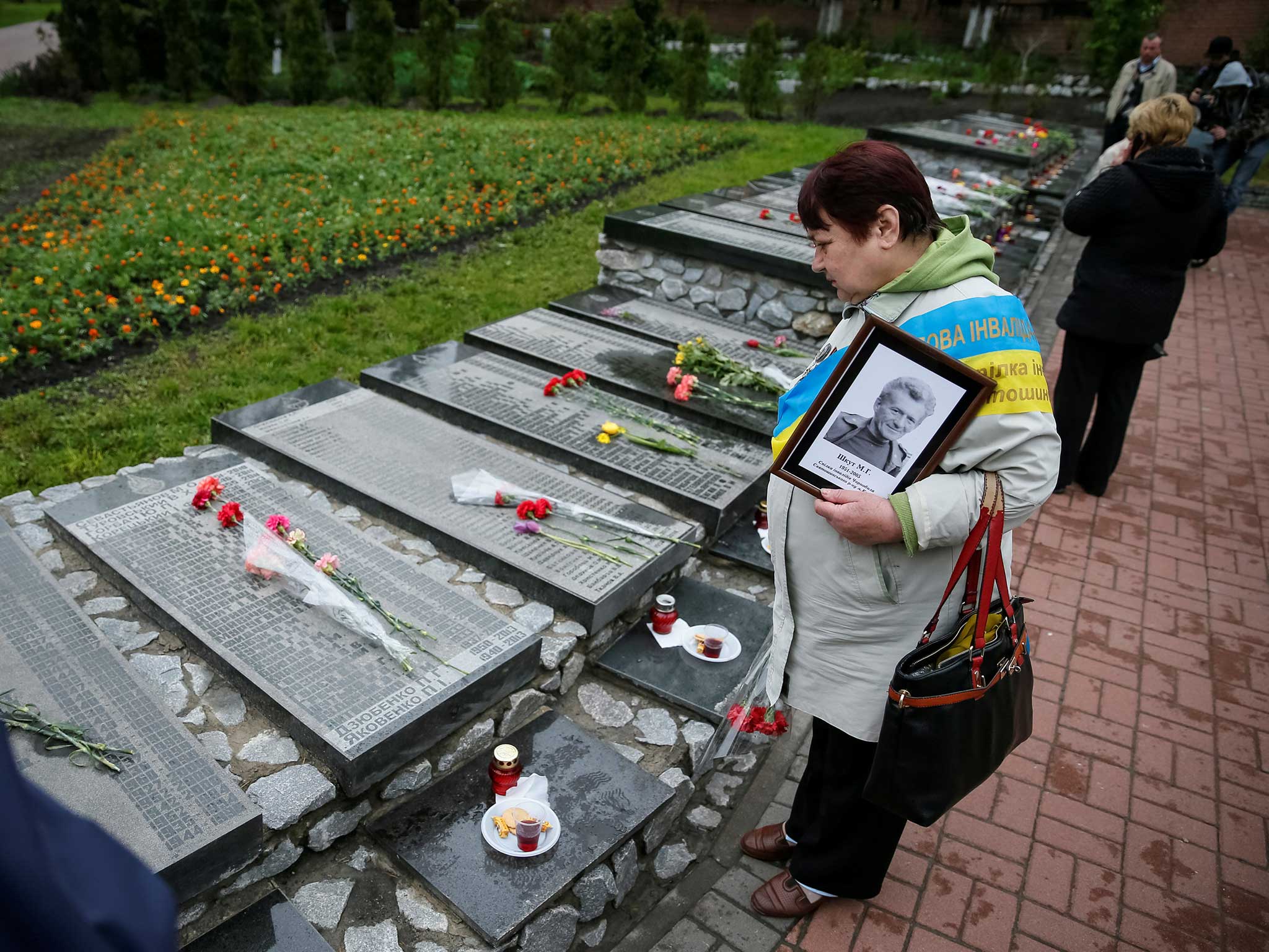 A woman holds a portrait of her relative, a victim of the Chernobyl nuclear disaster, as she visits  the memorial during a commemoration ceremony in Kiev