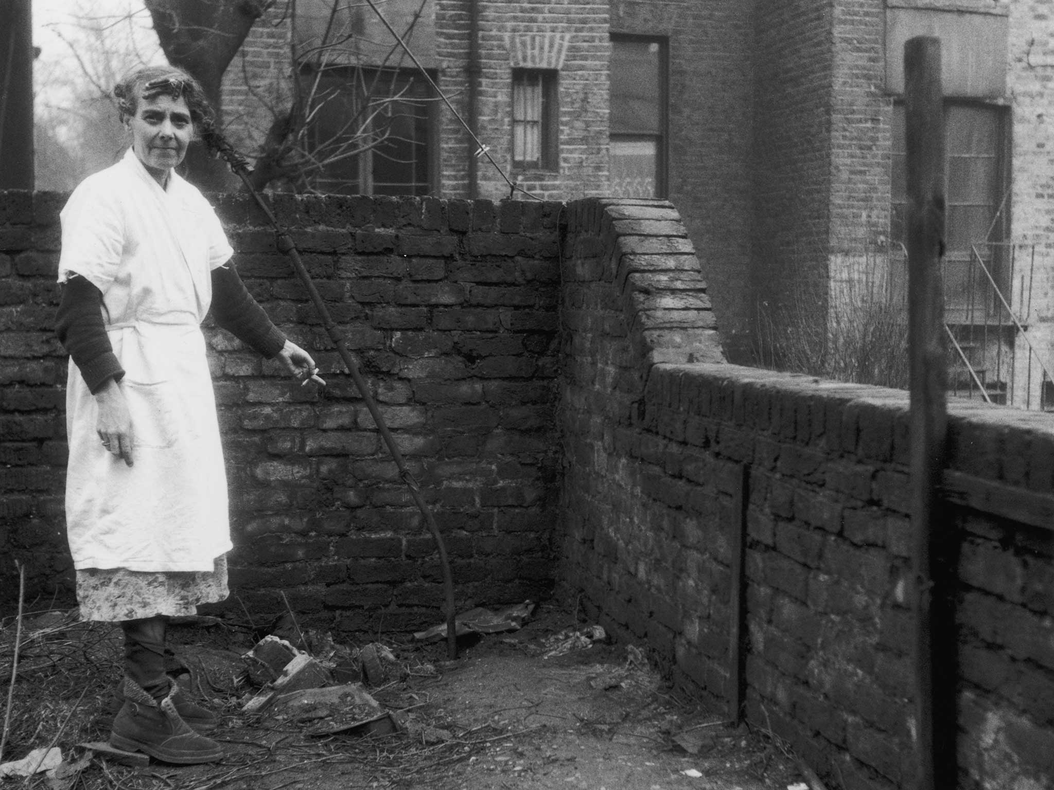 Mrs Hart, the neighbour of serial killer John Reginald Christie, points to the spot in the garden of 10 Rillington Place, where two of his victims were buried, circa 1953