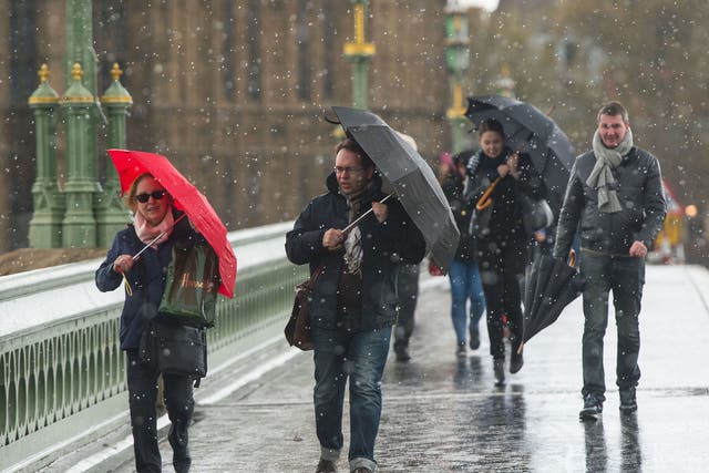 Pedestrians experience a brief snow shower on Westminster Bridge, in central London