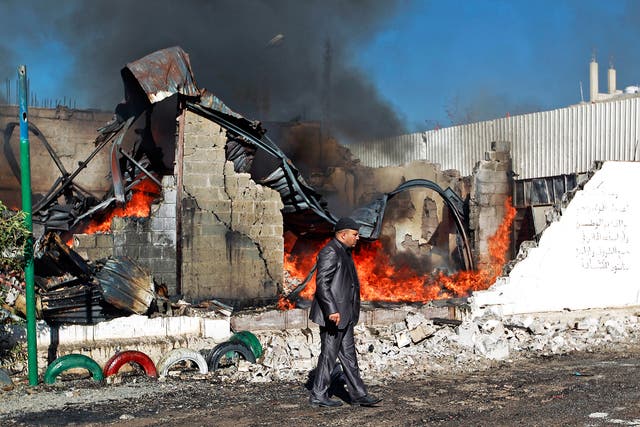 Flames rise from the ruins of a building destroyed by a Saudi air strike in Sanaa, Yemen, earlier this year