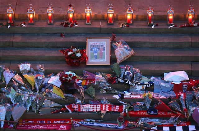 Tributes including flowers and scarfs lay below candles on the steps of St George's Hall