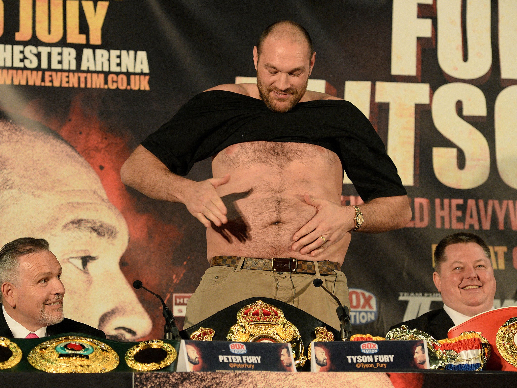 Tyson Fury takes off his t-shirt during a press conference