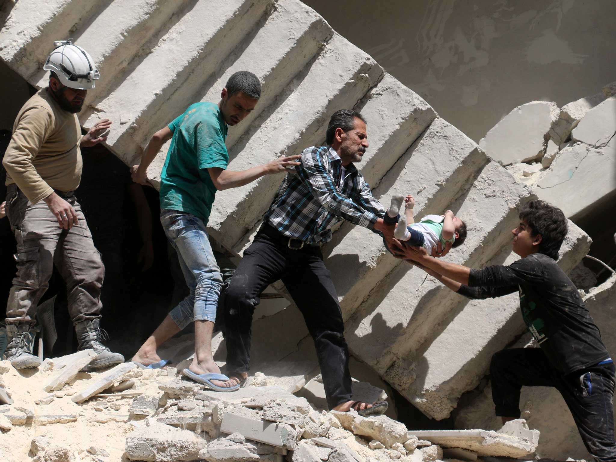 Syrian civil defence volunteers and rescuers remove a baby from under the rubble of a destroyed building following a reported air strike on the rebel-held neighbourhood of al-Kalasa in the northern Syrian city of Aleppo