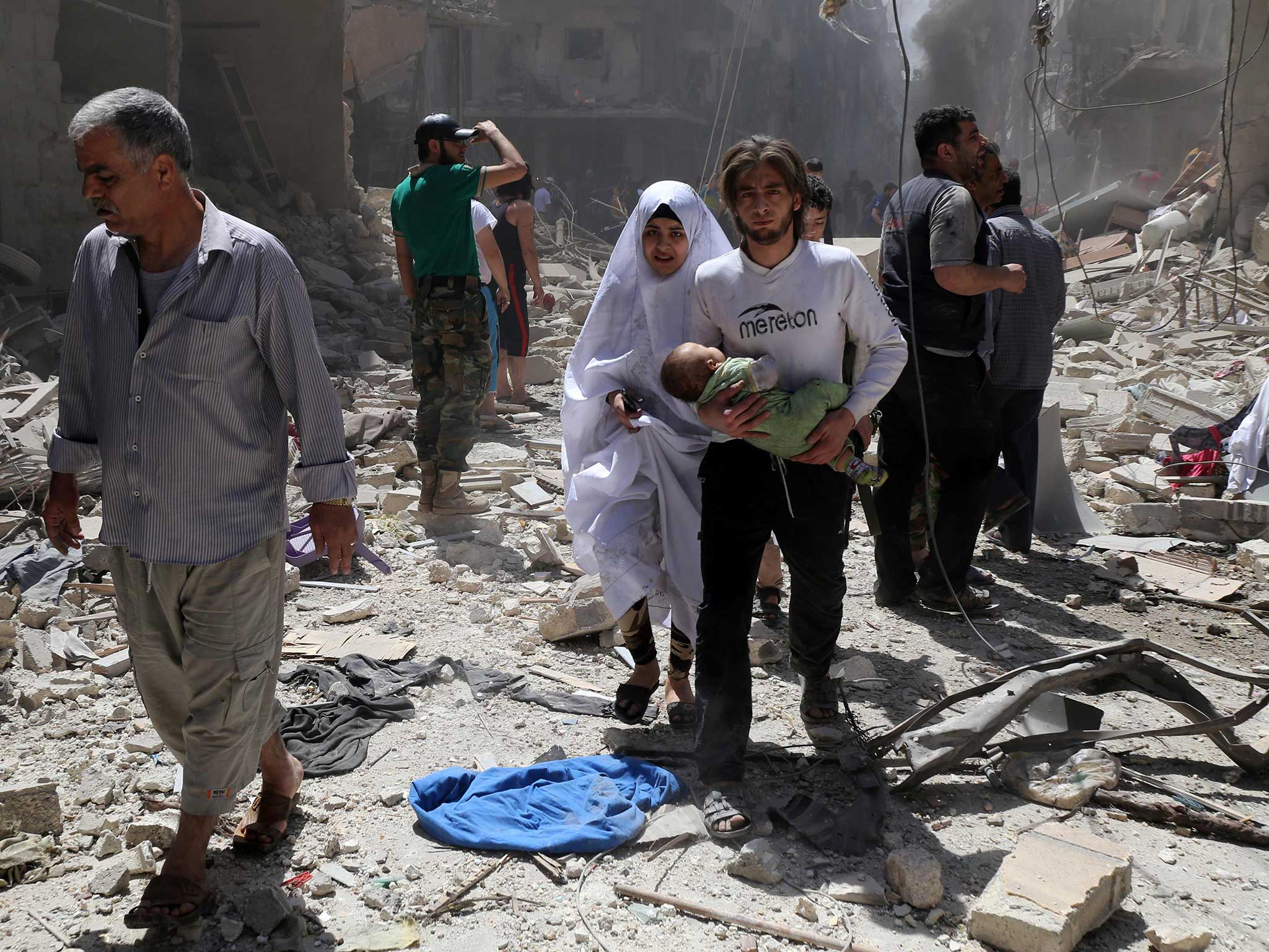A Syrian family walks amid the rubble of destroyed buildings following a reported air strike in the Bustan al-Qasr rebel-held district of the northern Syrian city of Aleppo