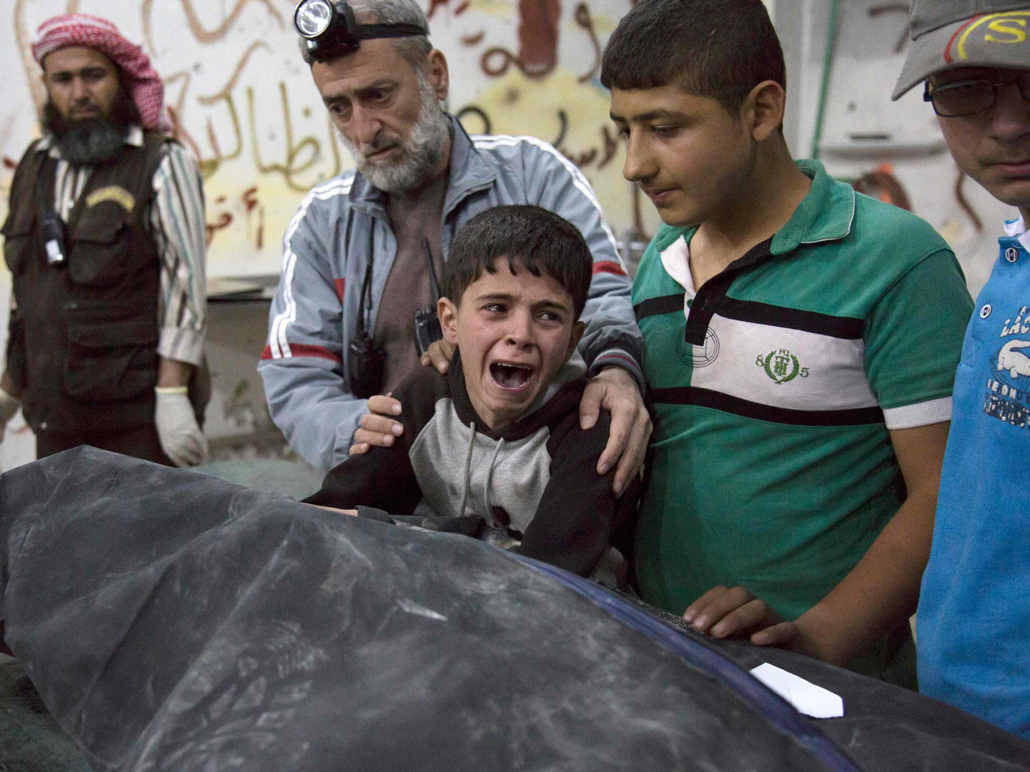 A Syrian boy is comforted as he cries next to the body of a relative who died in a reported air strike in the rebel-held neighbourhood of al-Soukour in the northern city of Aleppo