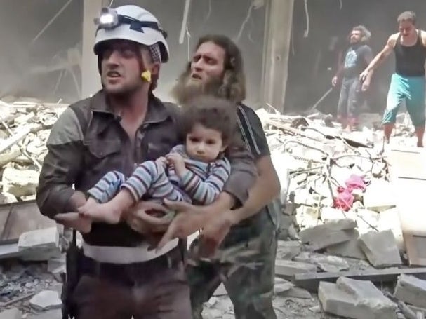 A Civil Defense worker carries a child after airstrikes hit Aleppo