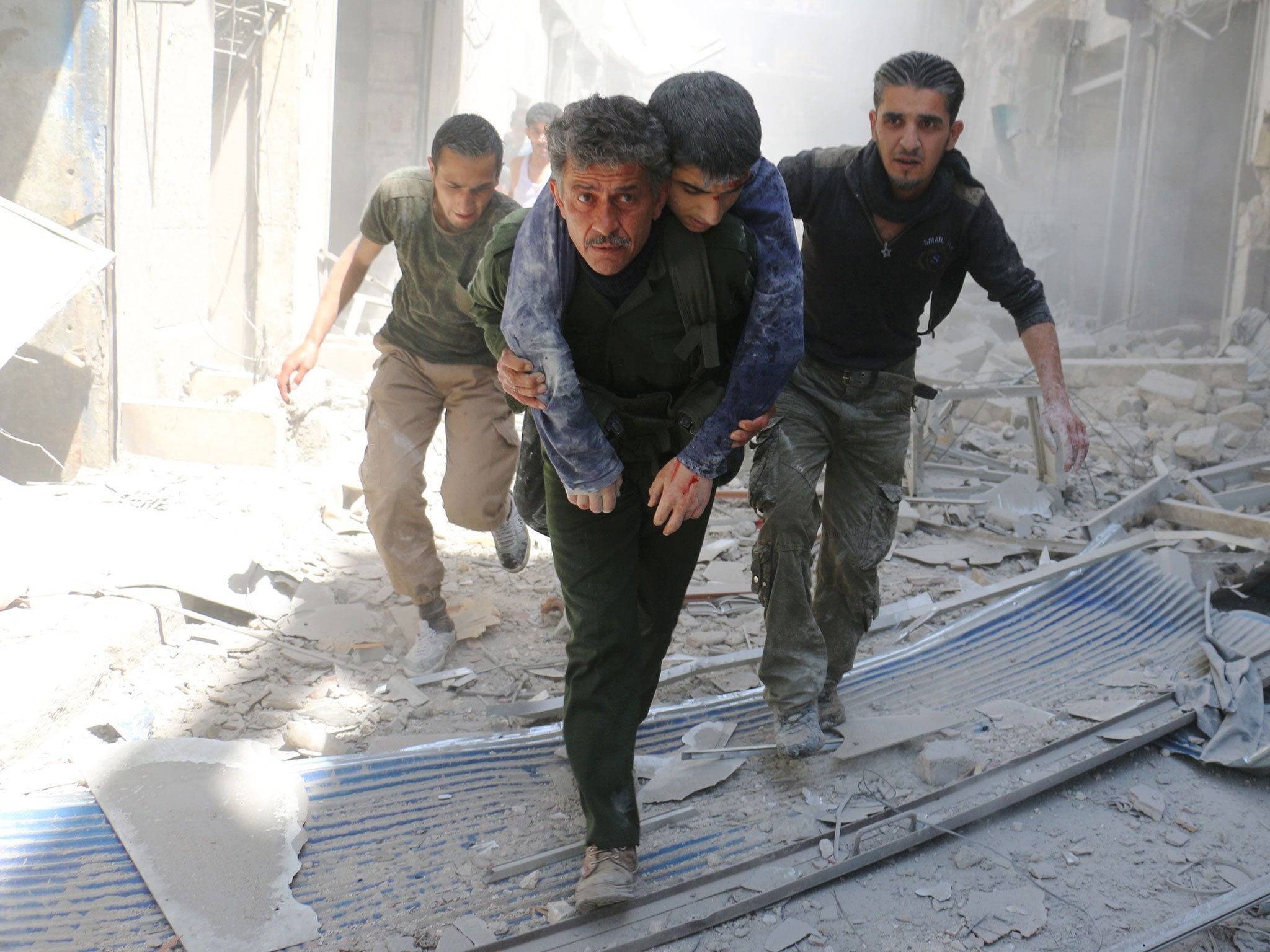 : Syrians evacuate an injured man amid the rubble of destroyed buildings following an air strike in Aleppo