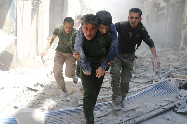 : Syrians evacuate an injured man amid the rubble of destroyed buildings following an air strike in Aleppo