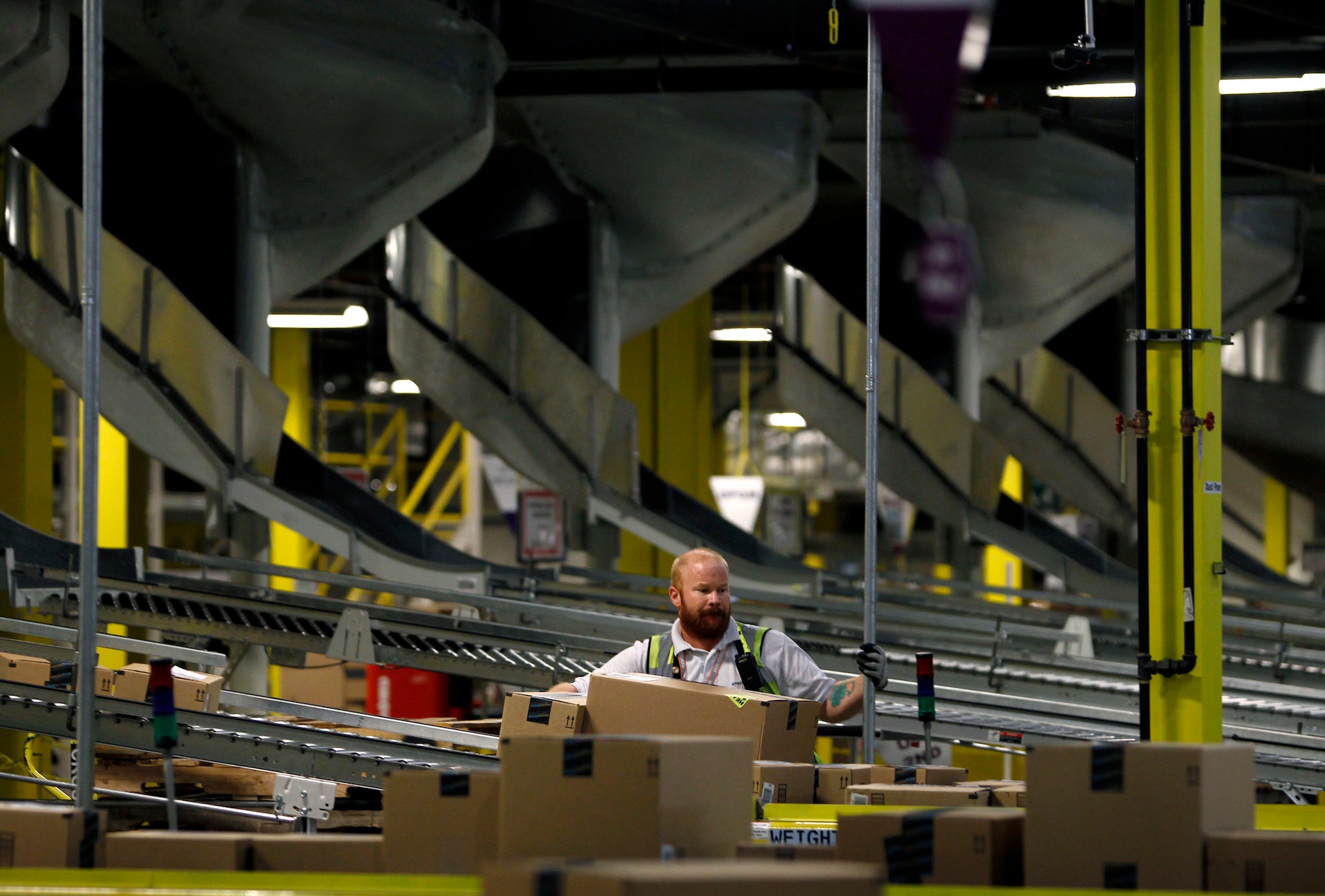 A worker keeps the flow of boxes for delivery moving in the shipping department at Amazon's distribution center in Phoenix, Arizona November 22, 2013