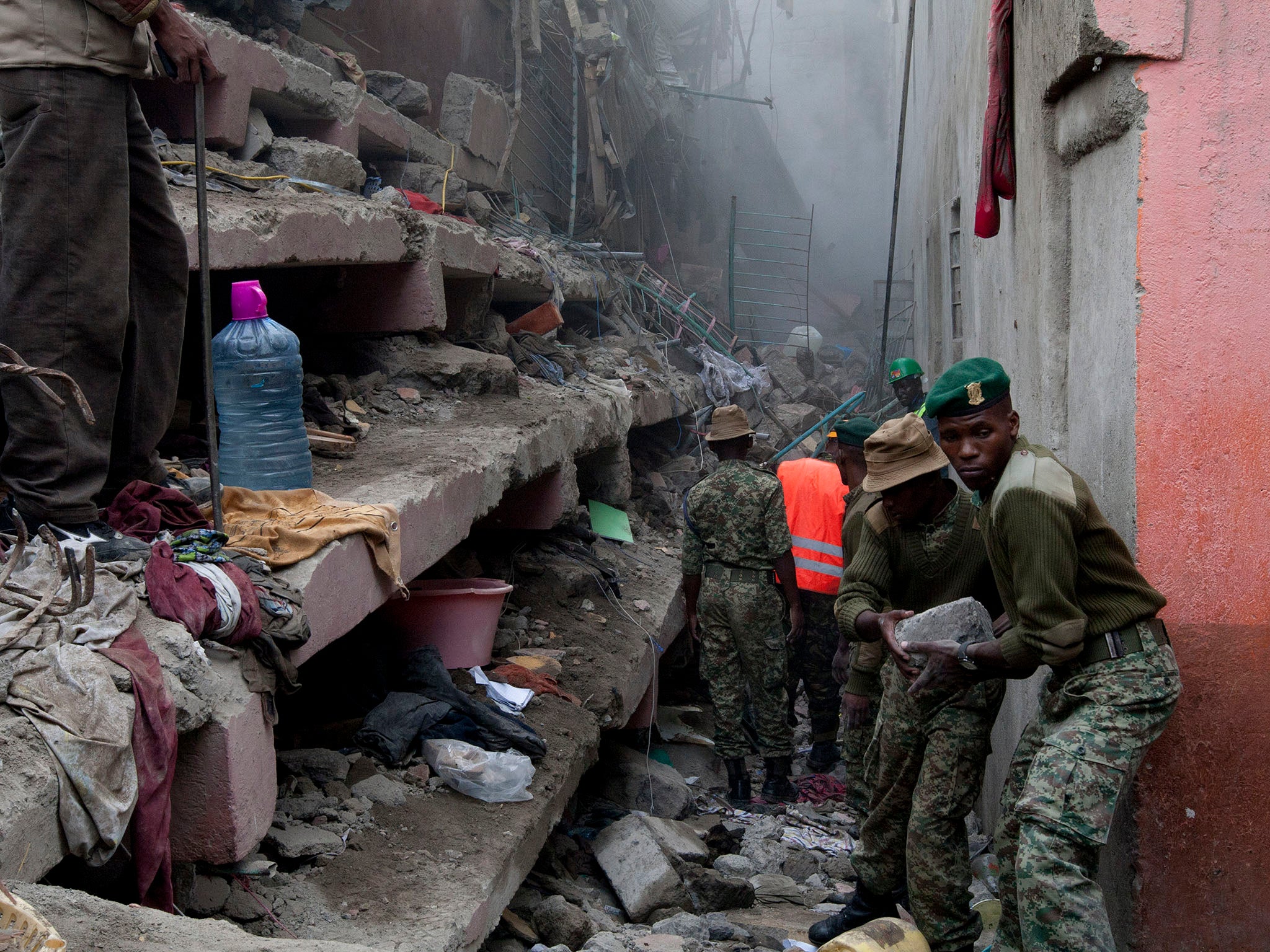 Kenyan National Youth Service personnel remove stones with hands at the site of a building collapse in Nairobi