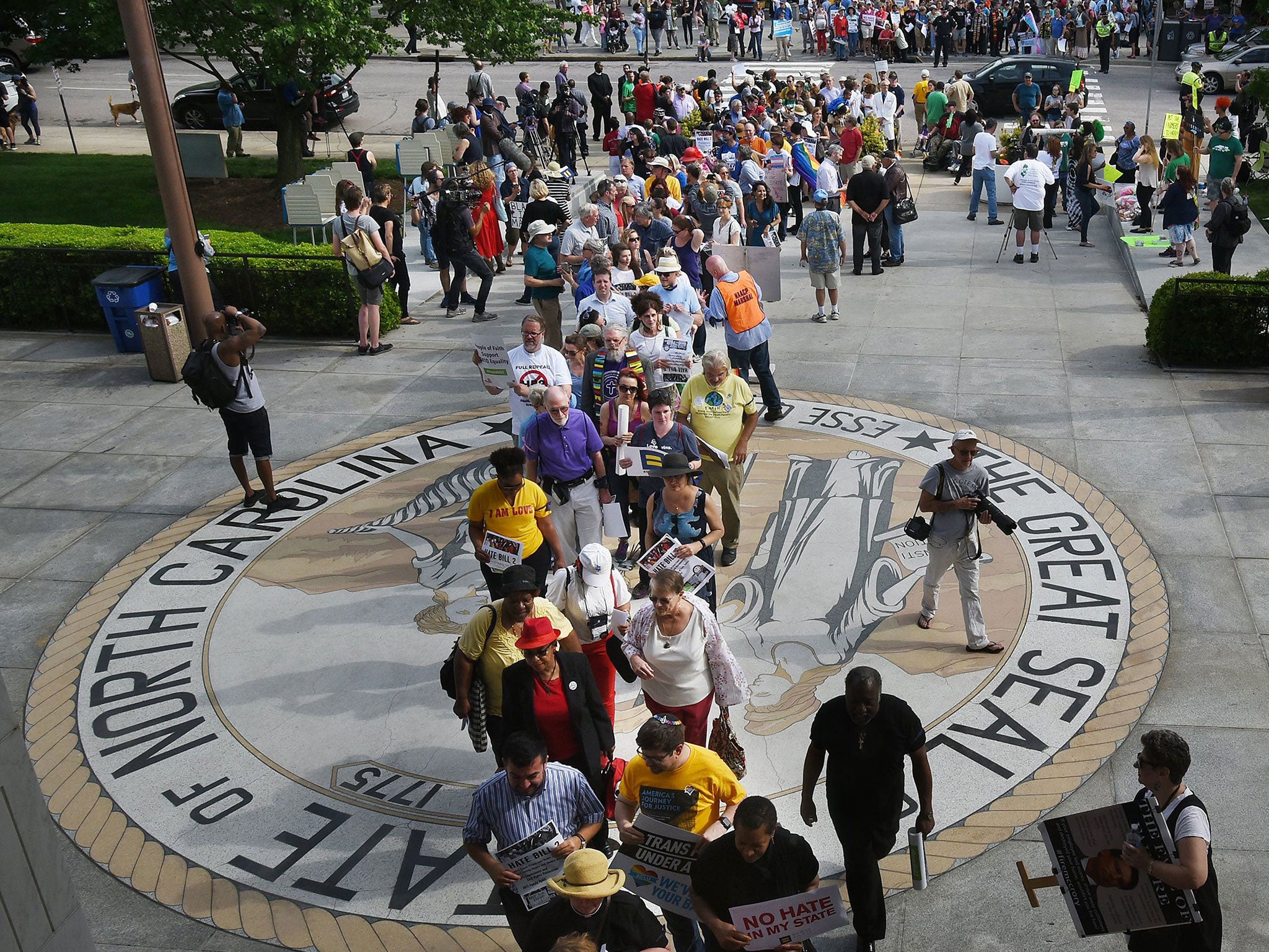 Opponents of North Carolina's HB2 walk over the state seal as they enter the legislative building for a sit-in protest in Raleigh
