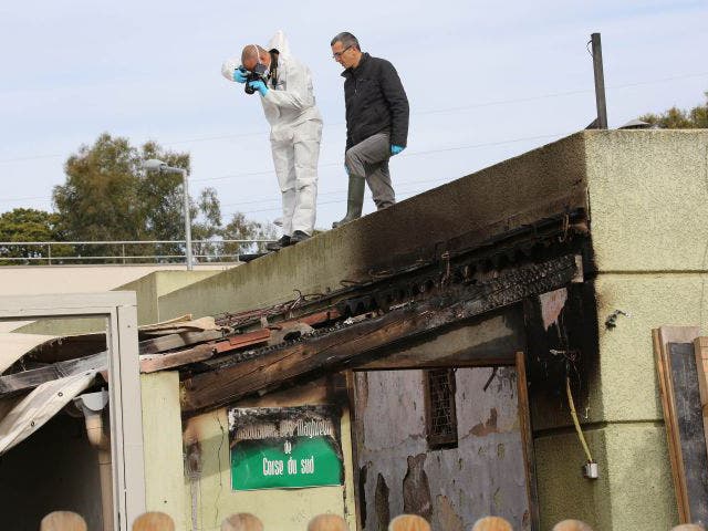 Police officers inspect a damaged Muslim prayer room set on fire