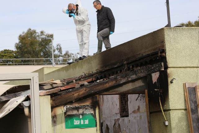 Police officers inspect a damaged Muslim prayer room set on fire