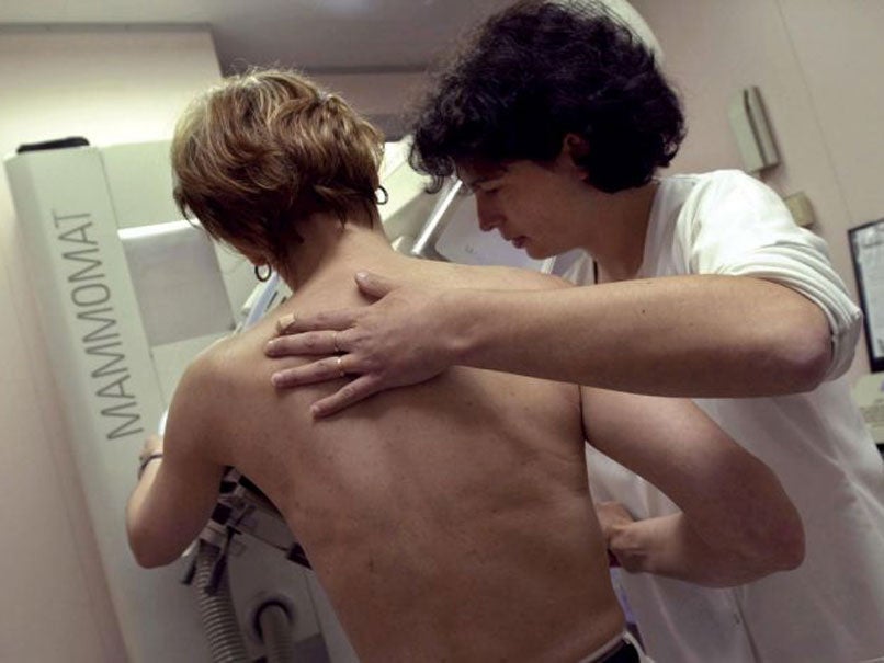 A nurse performs a mammography on a patient to check for signs of breast cancer