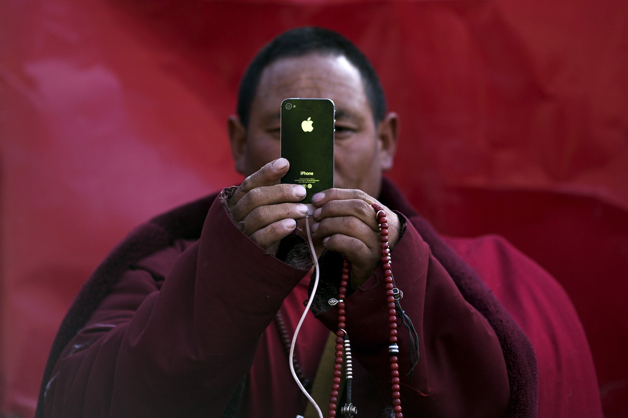 A Tibetan Buddhist monk takes pictures with his smartphone of a daily chanting session at a Buddhist laymen lodge during the Utmost Bliss Dharma Assembly, the last of the four Dharma assemblies at Larung Wuming Buddhist Institute in remote Sertar county, Garze Tibetan Autonomous Prefecture, Sichuan province, China early October 30, 2015