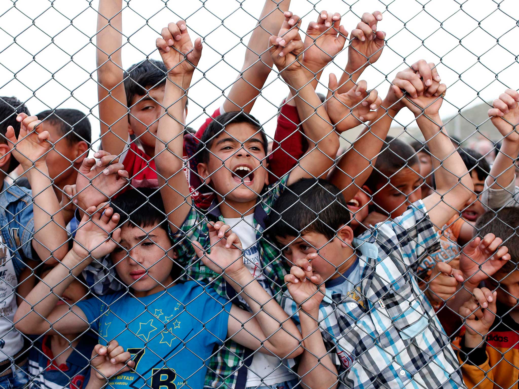 Syrian refugee children stand at a fence in Nizip district near Gaziantep, Turkey