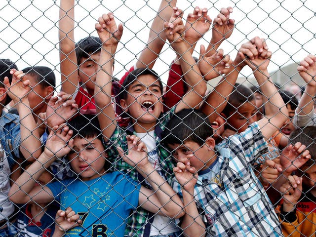 Syrian refugee children stand at a fence in Nizip district near Gaziantep, Turkey