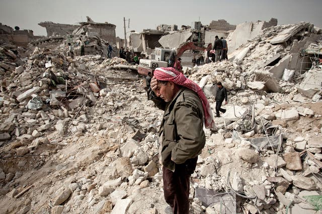 A Syrian man reacts while standing on the rubble of his house while others look for survivors and bodies in the Tariq al-Bab district of the northern city of Aleppo on 23 February, 2013