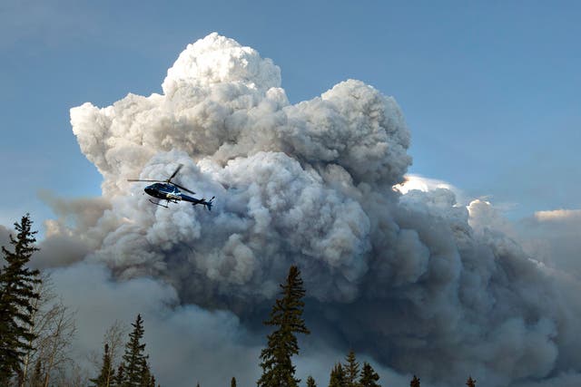 A helicopter flies past a wildfire in Fort McMurray, Alberta