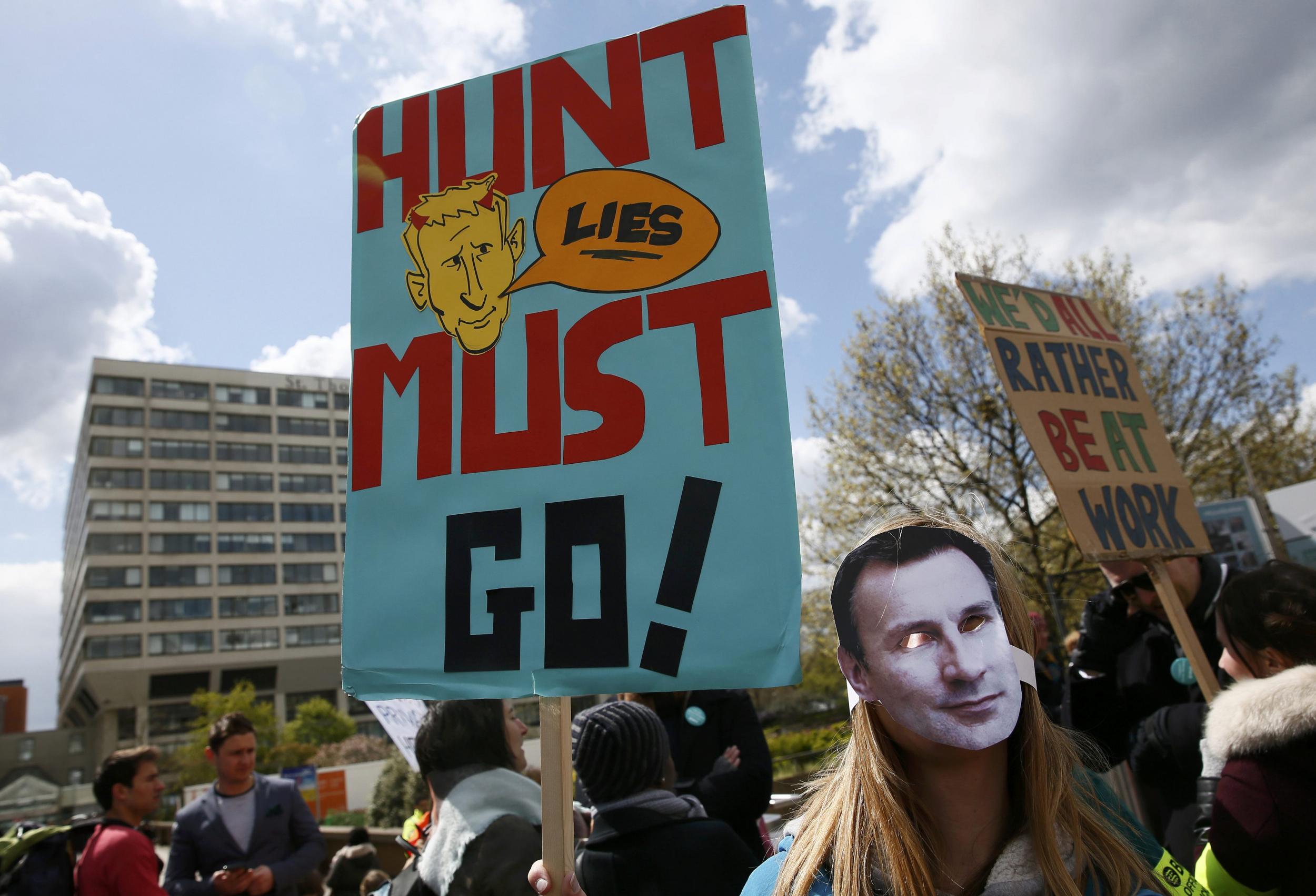A junior doctor wears a mask bearing the face of Health Secretary Jeremy Hunt during a strike outside St Thomas' Hospital in London,