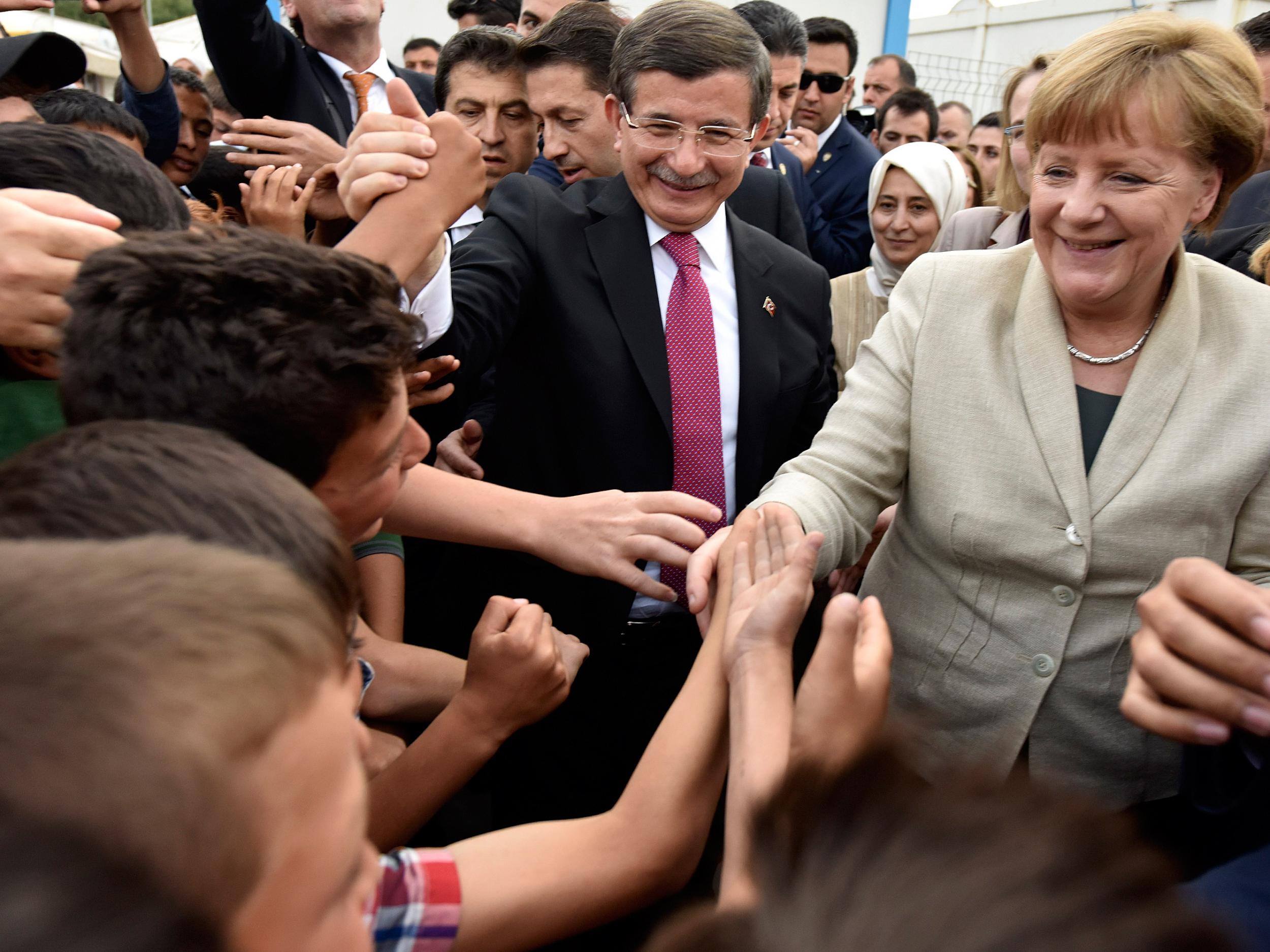 Turkey's Prime Minister, Ahmet Davutoglu and German Chancellor Angela Merkel greet people at a refugee camp on April 23, 2016 in Gaziantep, Turkey (Getty Images)